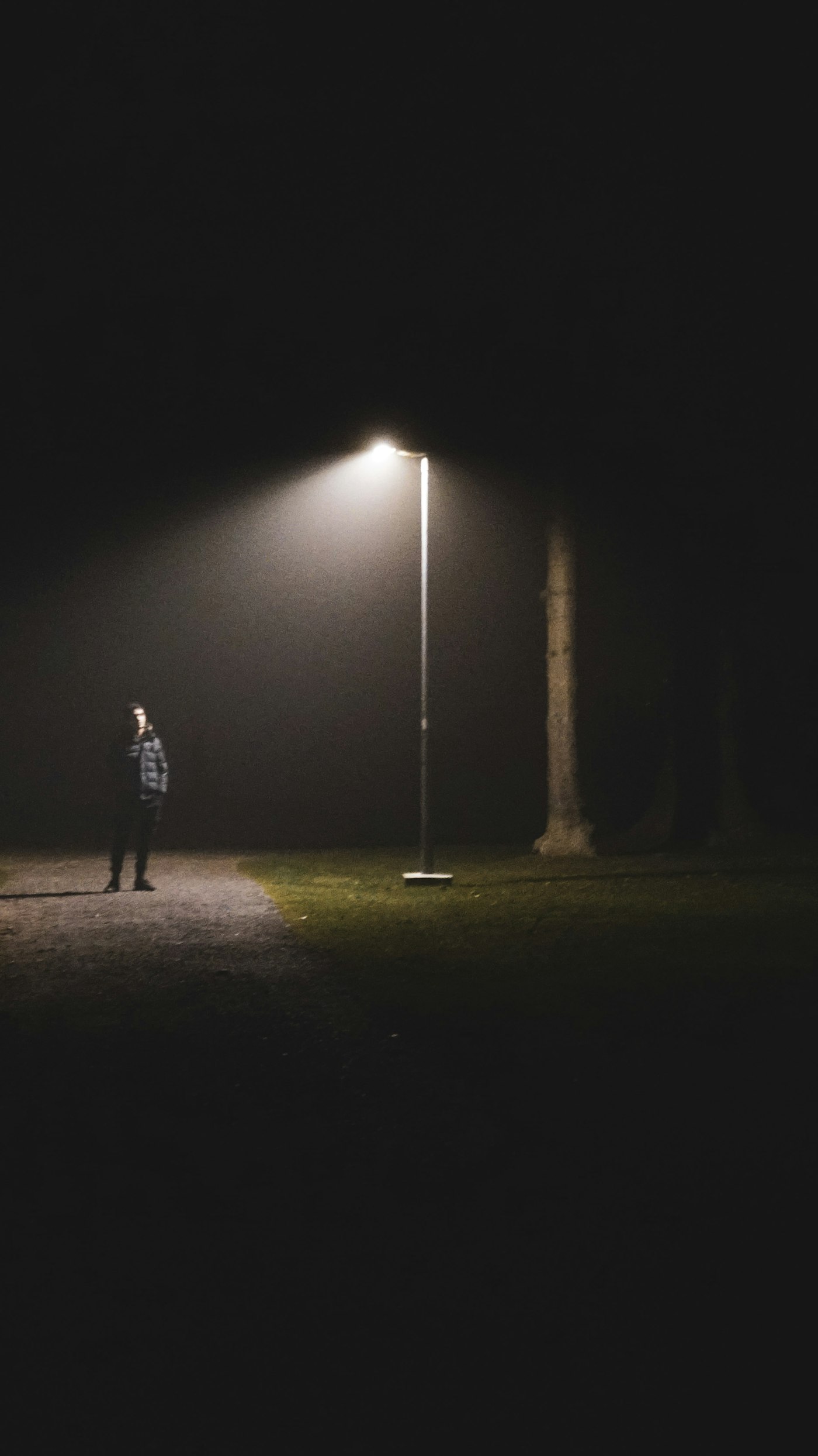 A lone figure standing in the dark, lit by a single streetlight, framed by a green detection box